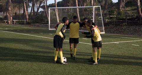 Youth Soccer Team Huddling on Field for Teamwork and Strategy