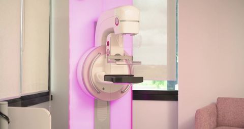Mammography unit glowing with pink backlight, modern clinic interior for breast screening