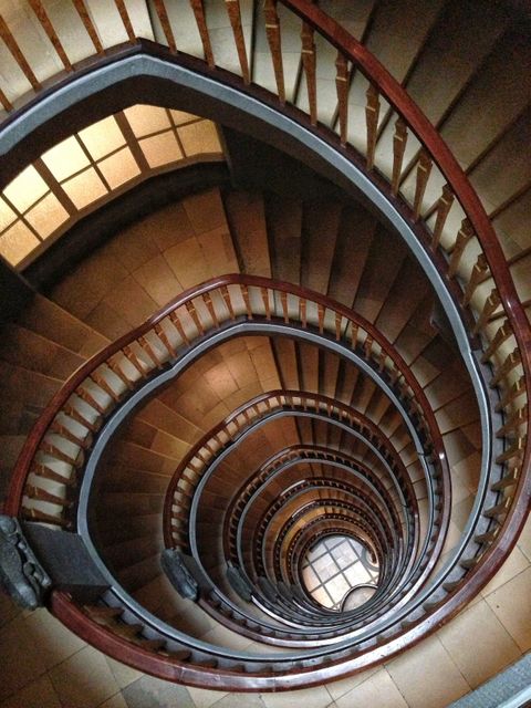 Stunning architecture of a spiral staircase with wooden railings and tiled floor. Ideal for real estate brochures, interior design magazines, and architectural portfolios. This photo captures the elegance and timeless appeal of vintage staircases.