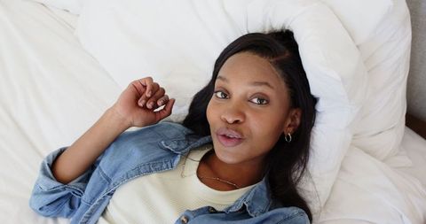 African American Woman Relaxing on Bed in Comfortable Denim Outfit