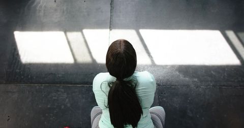 Mid adult african american woman sitting on gym bench under sunlight stripe