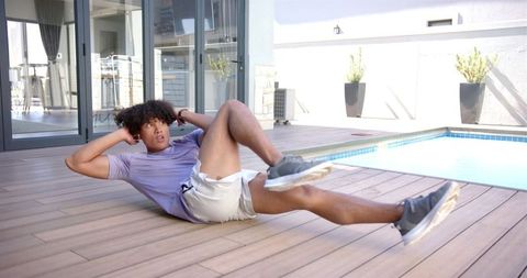 Young Man Doing Sit-ups by Pool in Backyard