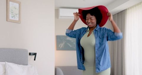 Joyful woman trying on red hat indoor