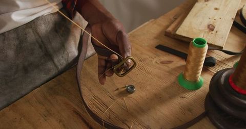 Skilled artisan crafting leather belt on workbench