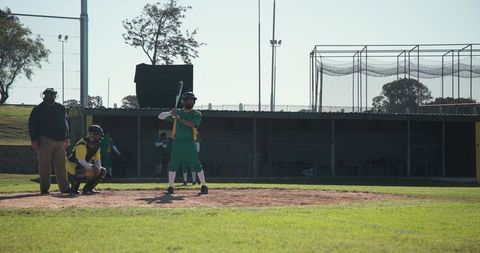 Batter Preparing at Home Plate During Amateur Baseball Game on Sunny Grass Field