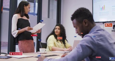 Woman presenting while colleagues listening during team meeting with laptop and charts