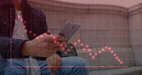Young man scrolling smartphone with declining financial analytics overlay on urban bench