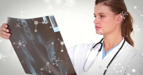 Female clinician examining pelvic x-ray while wearing stethoscope and medical scrubs