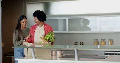 Diverse Couple Unpacking Groceries in Modern Kitchen Setting