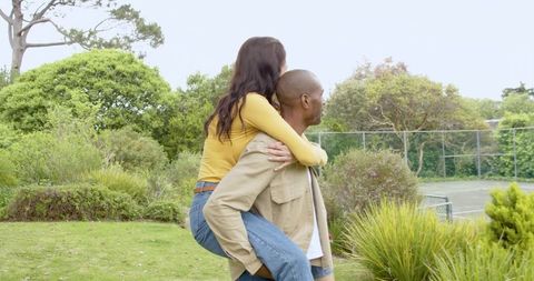 Happy couple enjoying outdoor piggyback ride in scenic park