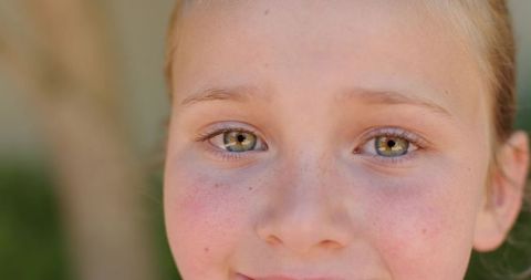 Close-up preteen girl smiling with green eyes and freckles, soft natural light portrait