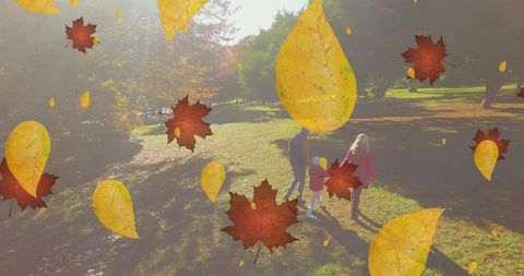 Family strolling through autumn park with falling leaves