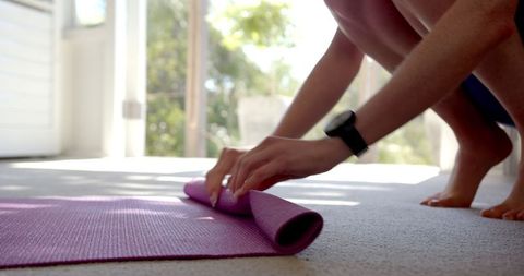 Woman Rolling Purple Yoga Mat After Home Workout