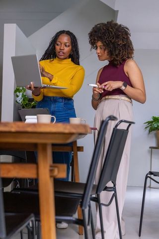 African american women collaborating over laptop in modern coworking space for teamwork
