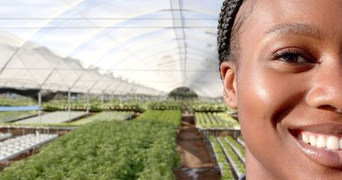 Smiling Woman in Hydroponic Greenhouse with Lush Plants