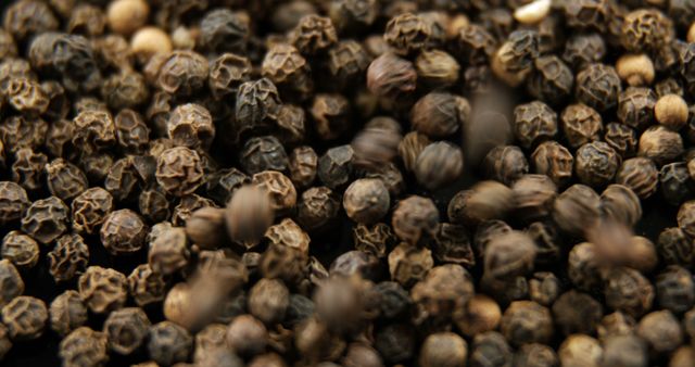 Close-up of black peppercorns, showcasing their texture and detail. Black pepper is a staple spice in cuisines worldwide, valued for its pungent flavor.