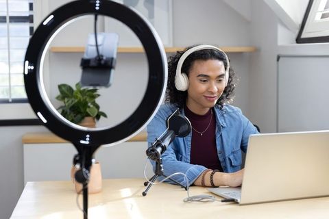 Nonbinary creator streaming podcast recording with ring light, microphone and laptop