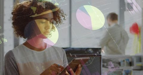 Tapping smartphone while analyzing mobile data overlays and charts in modern open office