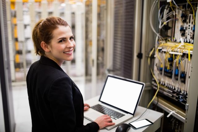 Portrait of technician using laptop while analyzing server in server room