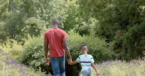 Father and Son Walking Through Lush Park Holding Hands - Download Free Stock Images Pikwizard.com