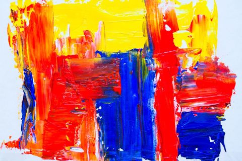 Vibrant acrylic brushstrokes creating bold red blue yellow abstract canvas texture
