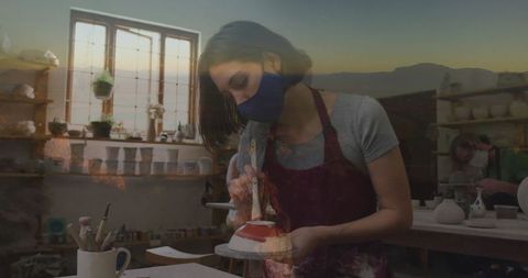 Artisan brushing glaze on ceramic in rustic potter's studio