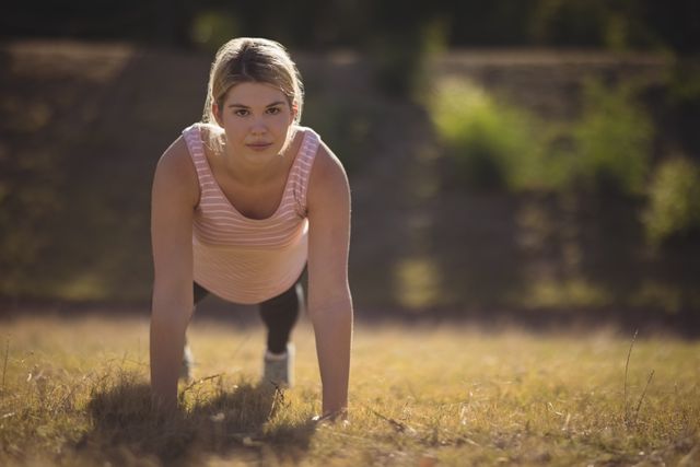 Woman performing exercise in outdoor boot camp, showcasing determination and strength. Ideal for fitness, health, and wellness promotions, as well as motivational content.
