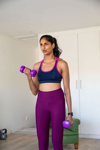 Determined woman lifting dumbbells in home workout setting