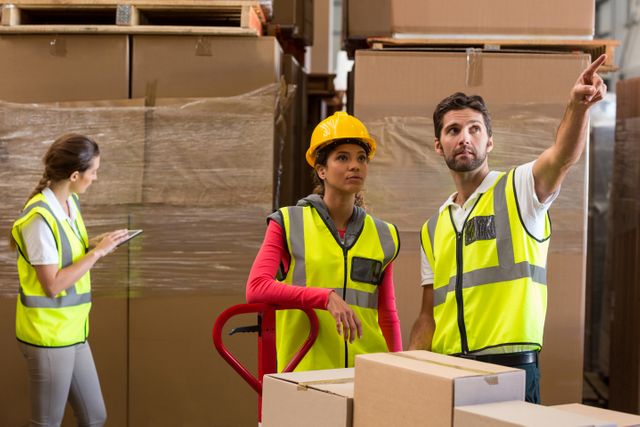 Warehouse workers discussing while preparing a shipment in warehouse