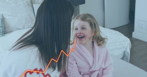 Mother leaning daughter laughing on bed in pink robe with orange zigzag graphic overlay