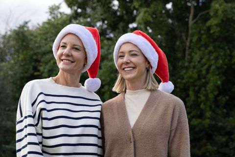 Senior friends smiling and wearing santa hats while posing in garden