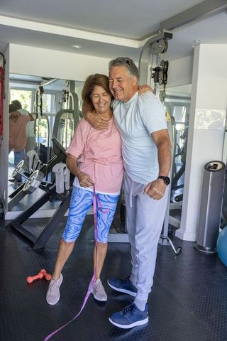 Mature couple embracing after home gym workout with pink resistance band