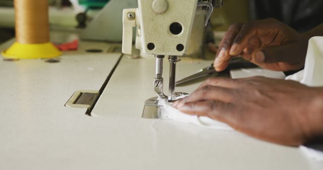 Hands of african american male tailor using sewing machine in workshop. Tailor, small business, work, labor and workshop, unaltered.