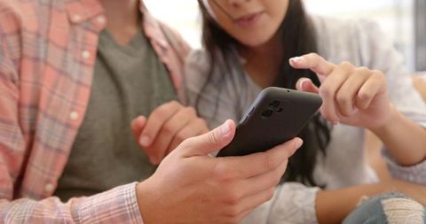 Couple using smartphone on couch in relaxed home environment