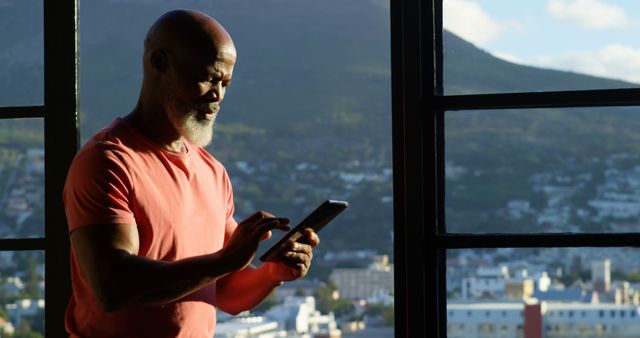 Senior Man Using Tablet by Window With City View - Download Free Stock Images Pikwizard.com