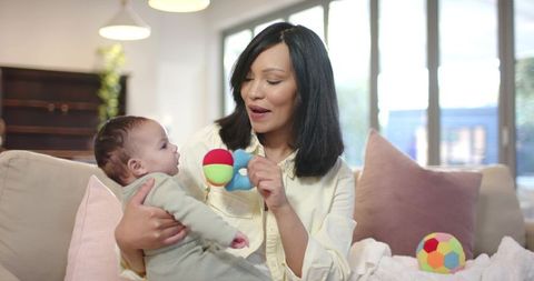 Mother Engaging Infant with Toy on Sofa in Cozy Living Room