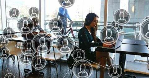 Businesswoman typing on laptop in modern campus cafe with digital network avatars overlay