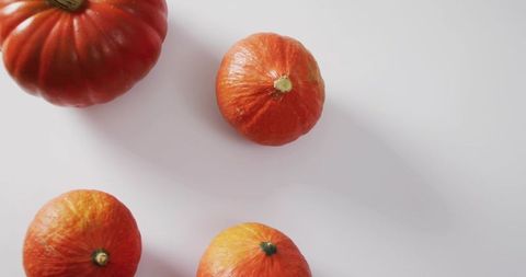 Minimal overhead pumpkins casting soft shadows on white tabletop for autumn
