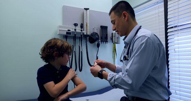 Doctor administering vaccine to young boy in a medical clinic room. Ideal for use in articles about child healthcare, vaccination awareness, pediatric consultations, immunization programs, and medical services.