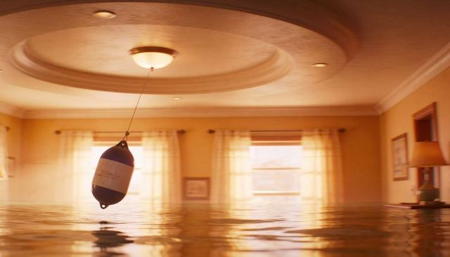 Dark buoy swinging above water in flooded golden living room with circular ceiling