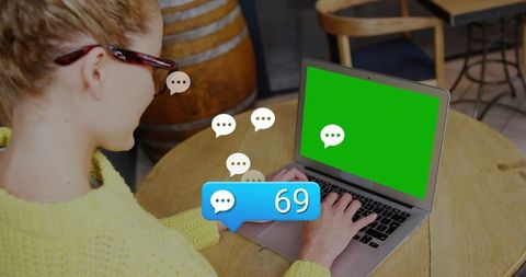 Woman typing on laptop in cozy coffeehouse with prominent chat notification bubble 69