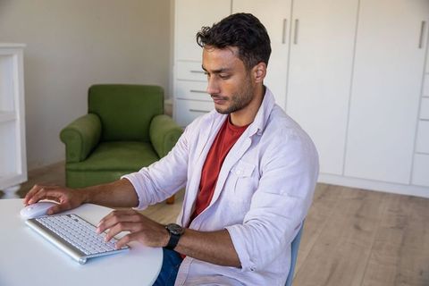 Focused man typing on wireless keyboard at home office