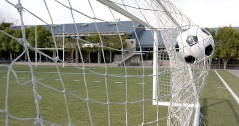 Soccer Ball Hitting Goal Net on Green Turf Field