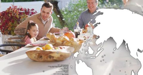 Multigenerational family sharing sunny outdoor meal on patio with subtle world map overlay