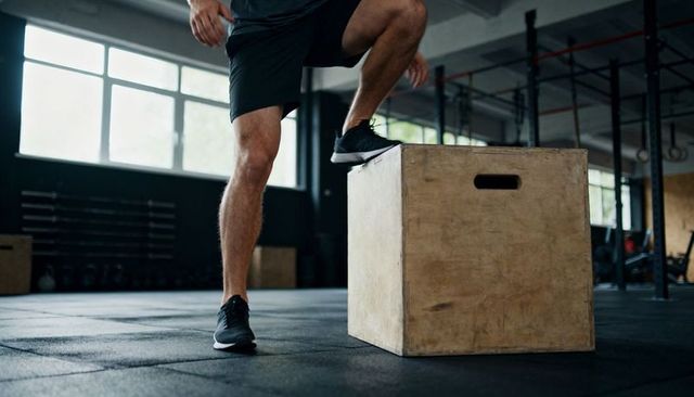 Athlete stepping onto plyo box during functional training in industrial gym