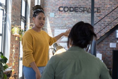 Diverse Female Colleagues Collaborating on Code at Modern Office