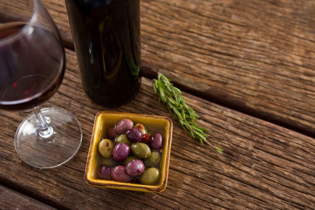 Close-up of marinated olives with glass of wine on table