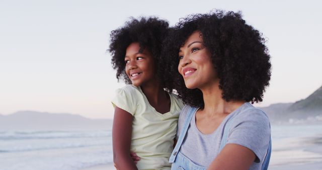 African american mother and daughter smiling looking at each other at the beach. family travel vacation leisure concept