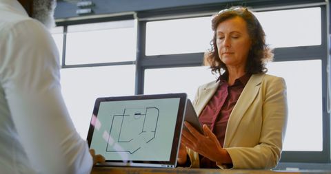 Caucasian Businesswoman Reviewing Digital Blueprint in Modern Office