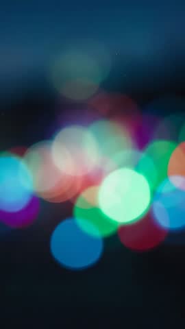 Vertical bokeh lights glowing on dark backdrop for dreamy colorful abstract video loop